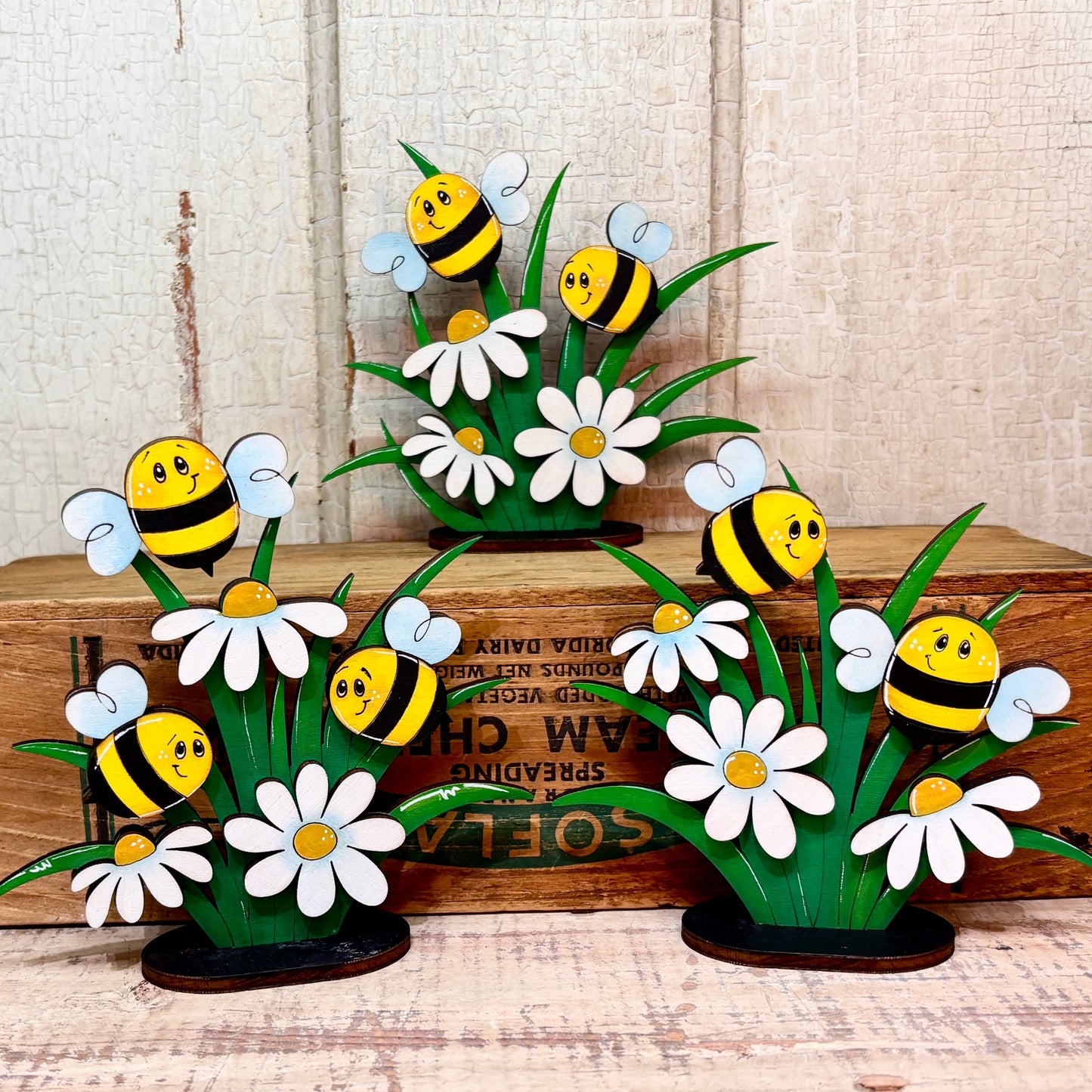 Decorative set of bees and daisies on a wooden surface.