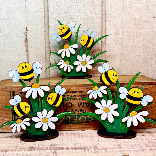 Decorative set of bees and daisies on a wooden surface.